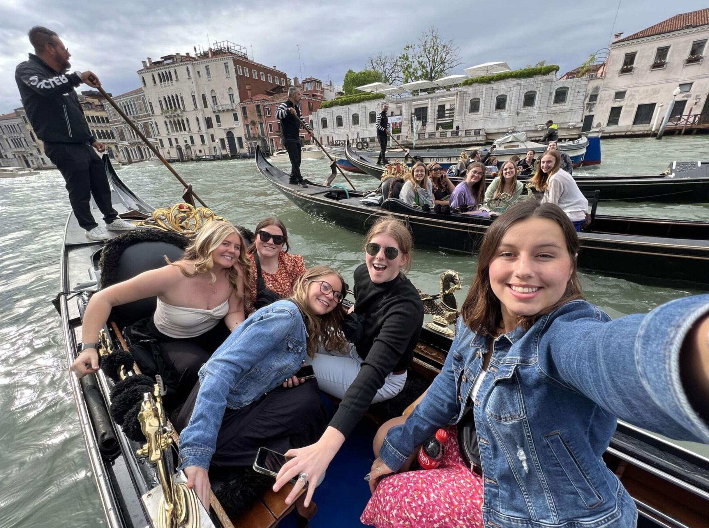 Education students pose for a selfie while riding multiple gondolas through Venice, Italy